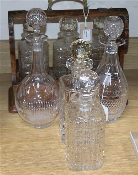 An oak three-decanter tantalus and four various glass decanters and stoppers